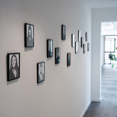 Im hellen, lichtdurchfluteten Flur mit der Mitarbeitergalerie an der Wand